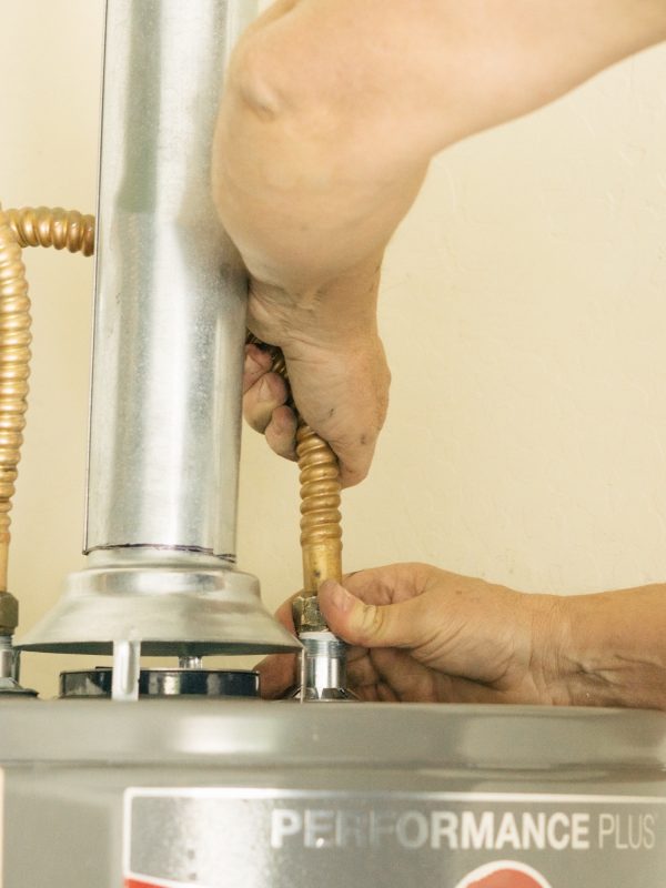 Adult male hands on water line going into a hot water heater